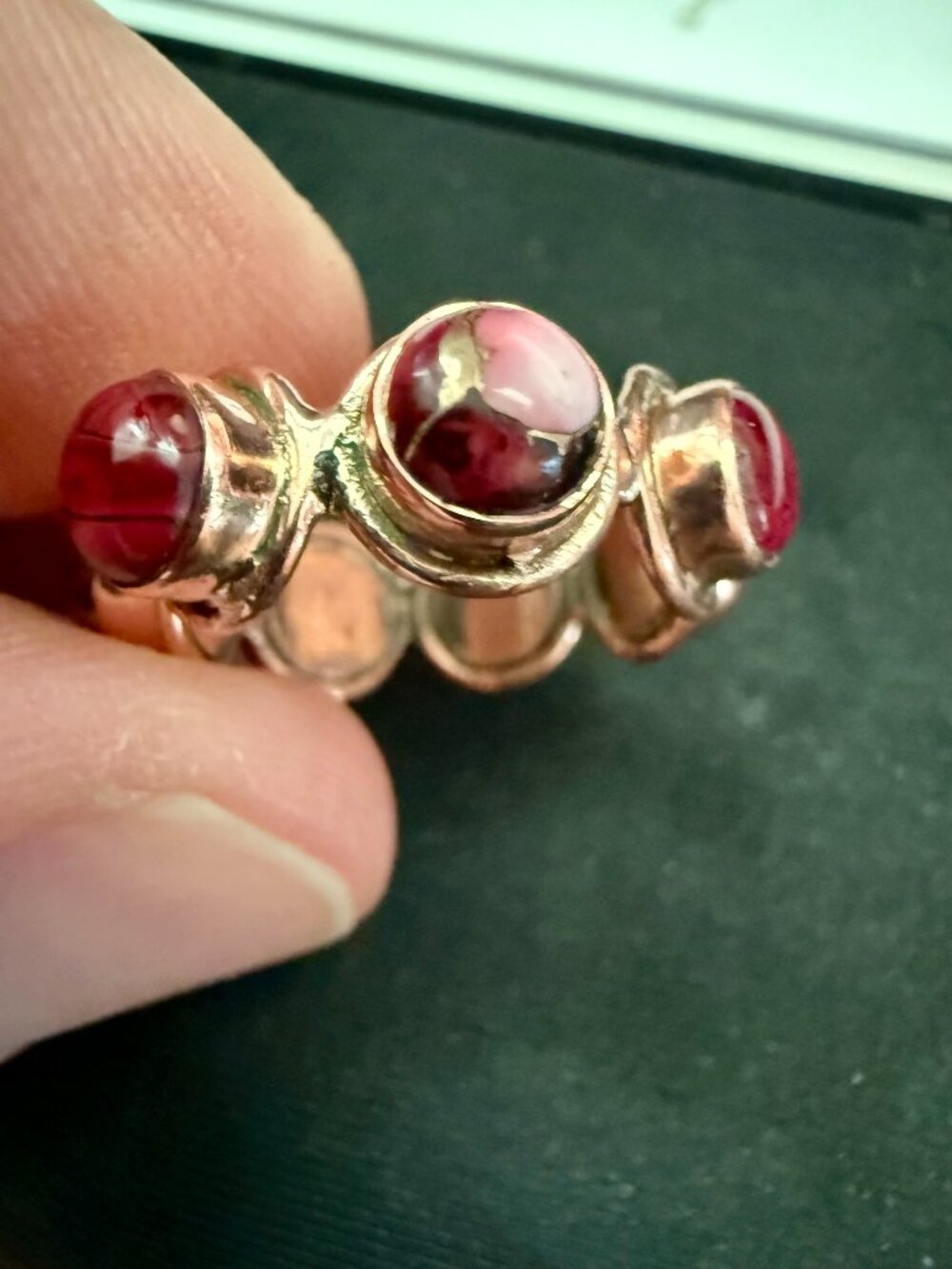 Copper bezel-set cabochon ring featuring pink stones with copper inclusions